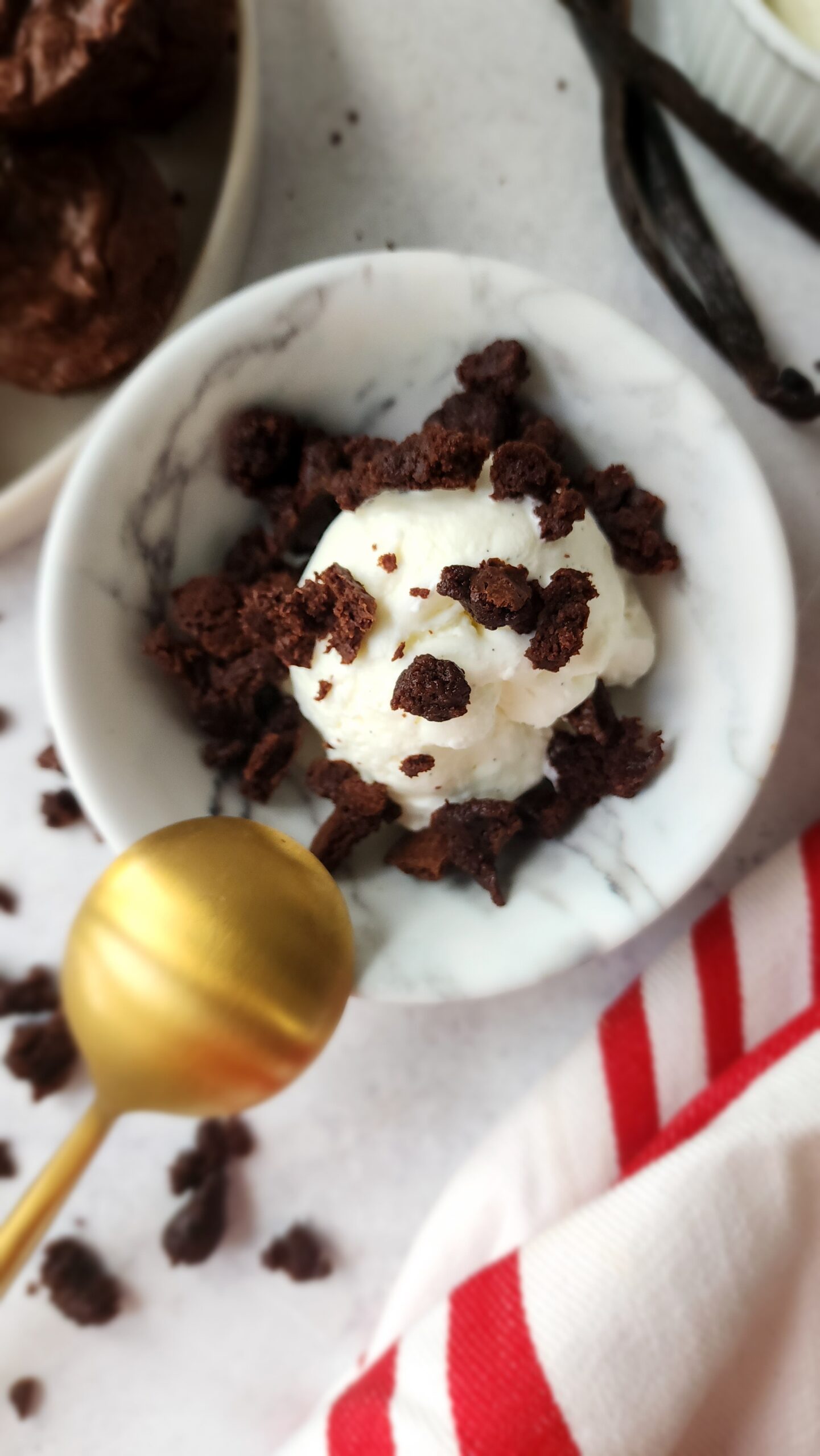 Close-up shot of a bowl of vanilla ice cream with brownie bits crumbled on top