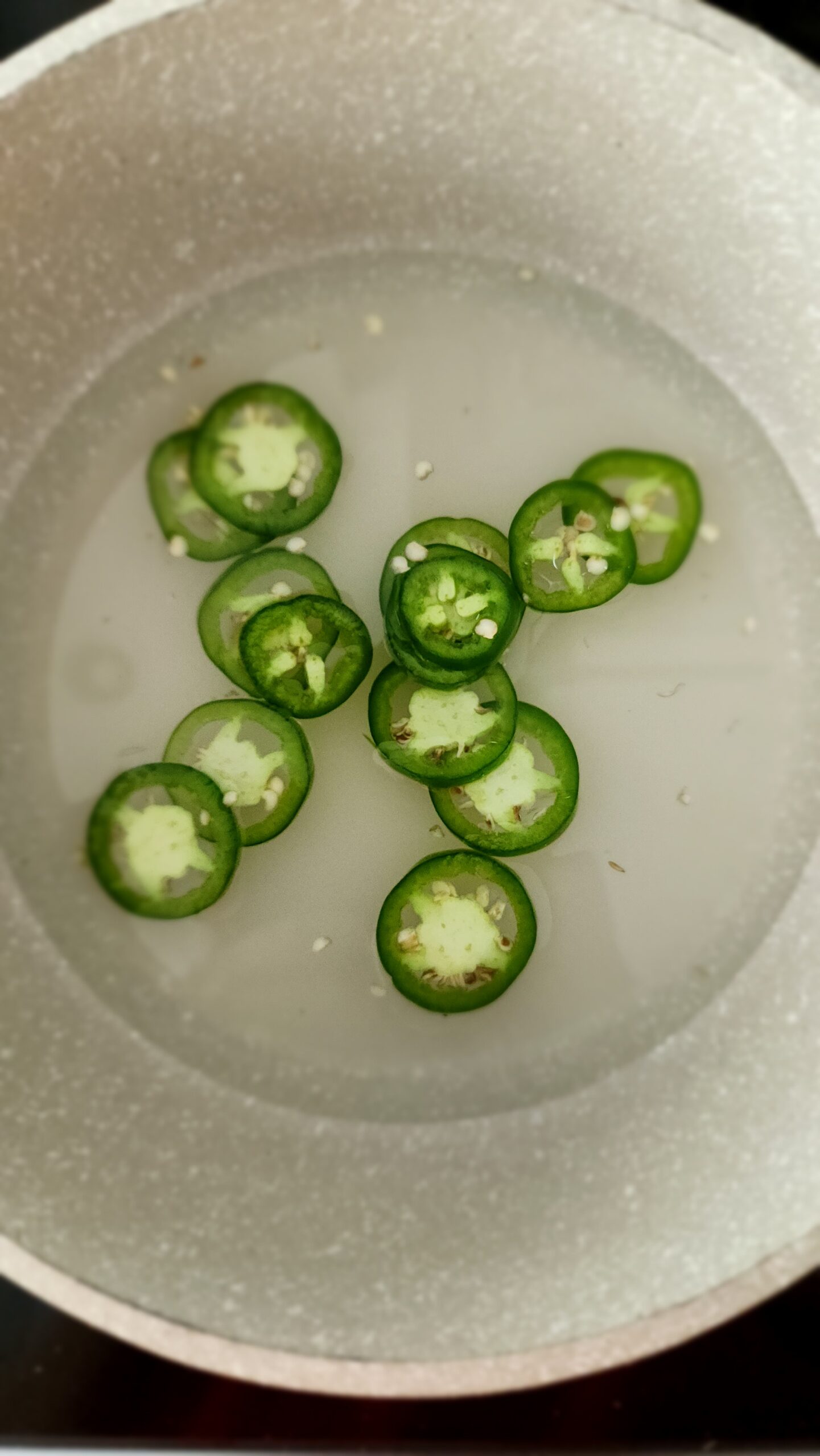 jalapeño slices in water with sugar in a saucepan