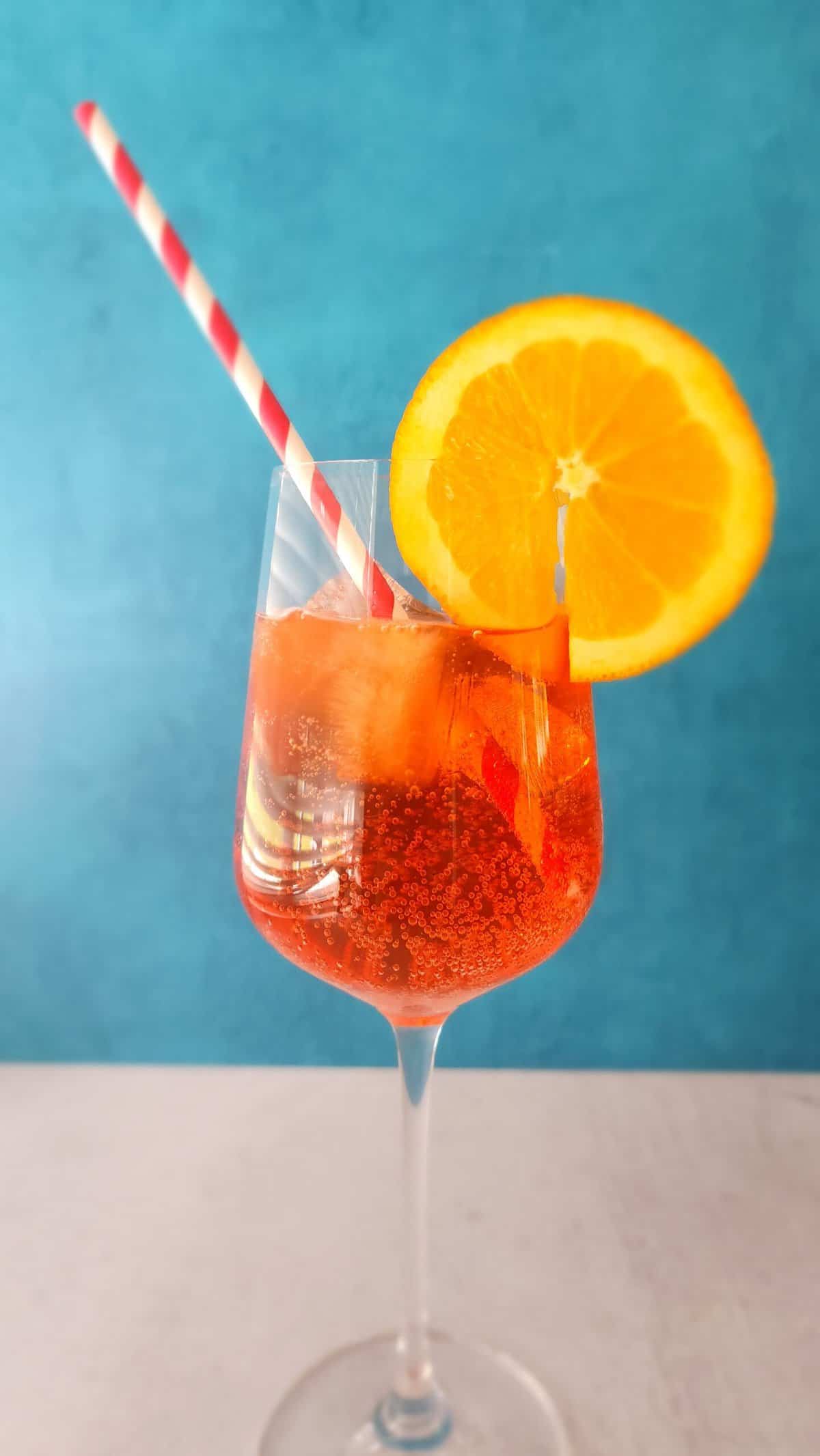 Glass of Aperol Spritz with a straw and slice of orange as garnish