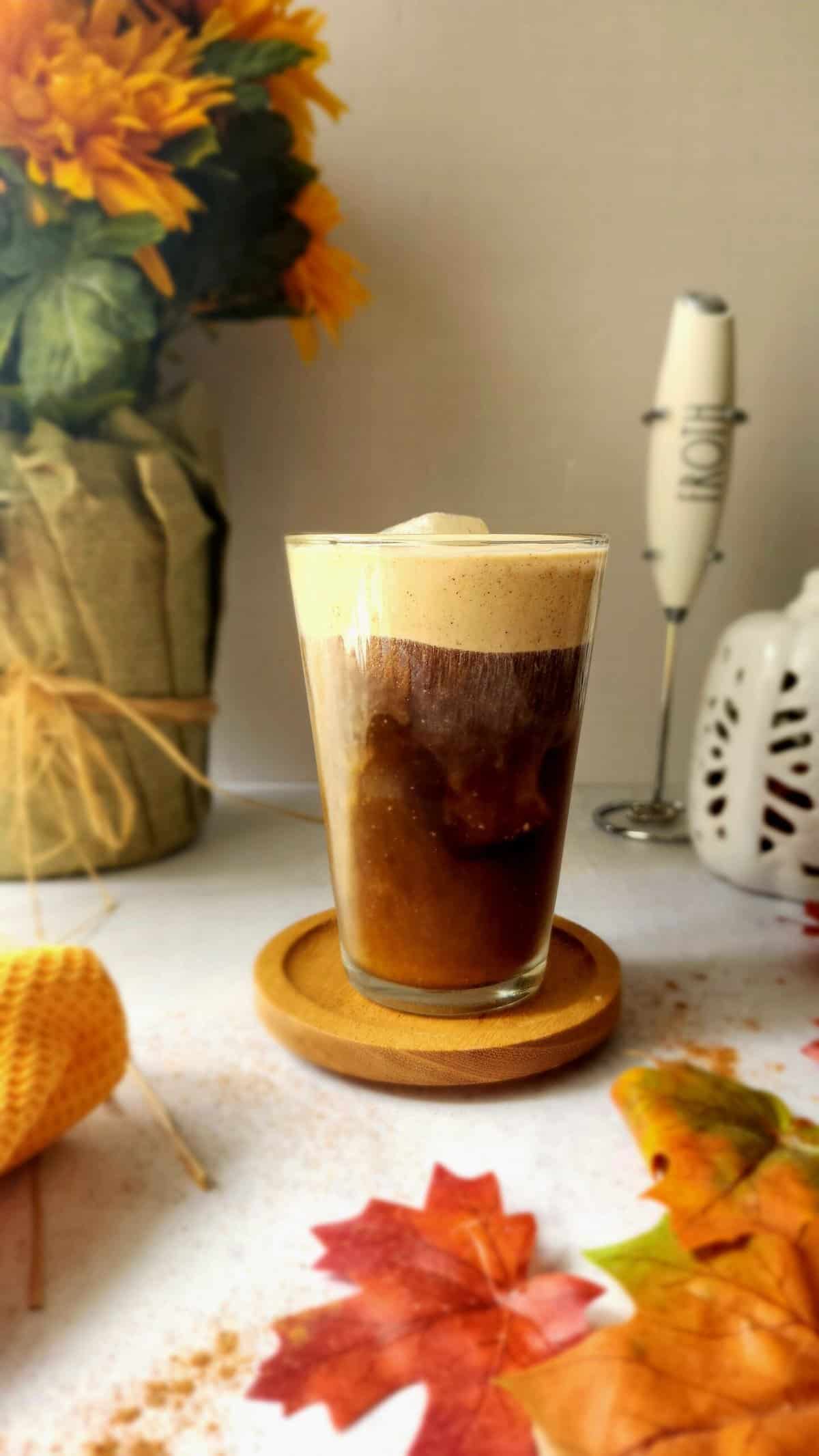 Pumpkin Cream Cold Brew in a glass with leaves and a mum