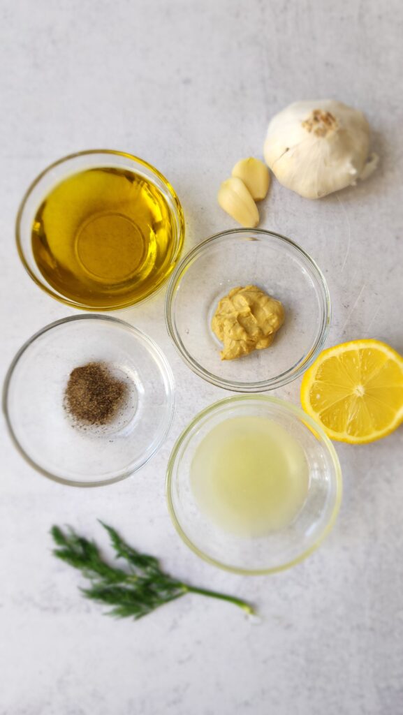 ingredients for lemon vinaigrette - dijon mustard, black pepper, garlic, extra-virgin olive oil, and dill