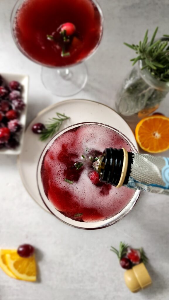 Top shot of prosecco being poured over pomegranate juice for pomegranate mimosas