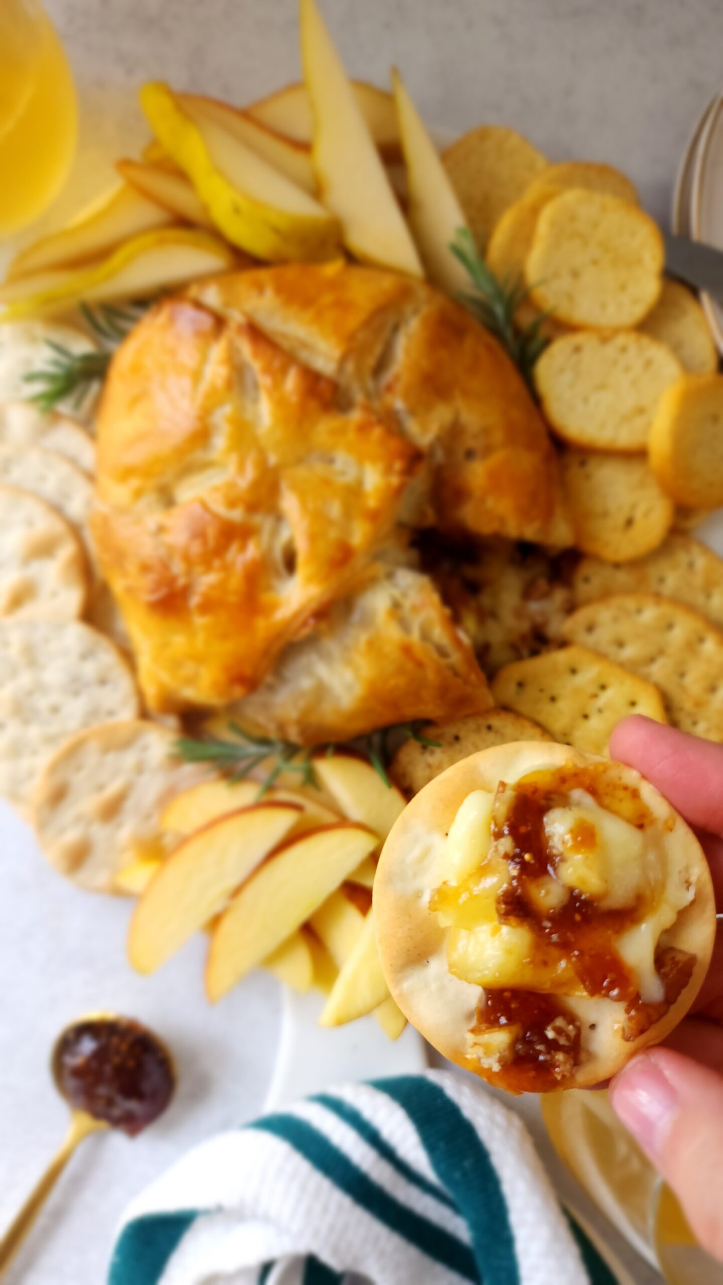 Baked Brie in Puff Pastry with some smeared on a cracker with fig jam and pecans