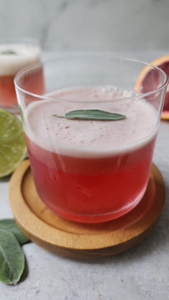 45 degree angle of a blood orange mocktail with a sage leaf on top