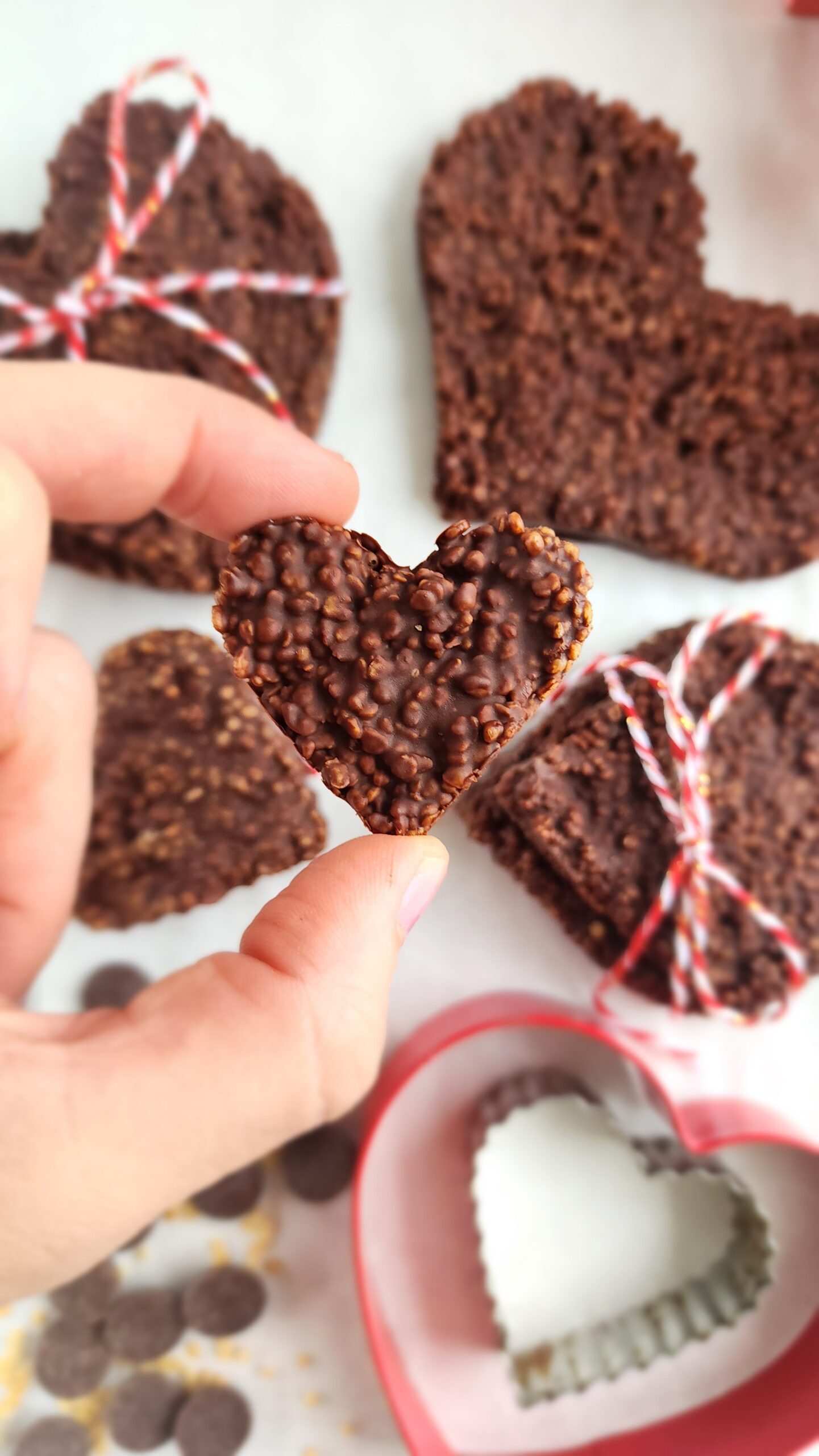 chocolate quinoa crunch in a heart shape being held in between two fingers