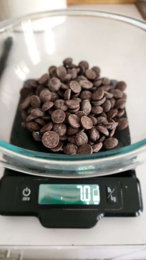 chocolate chips in a bowl getting weighed on a scale at 7 ounces