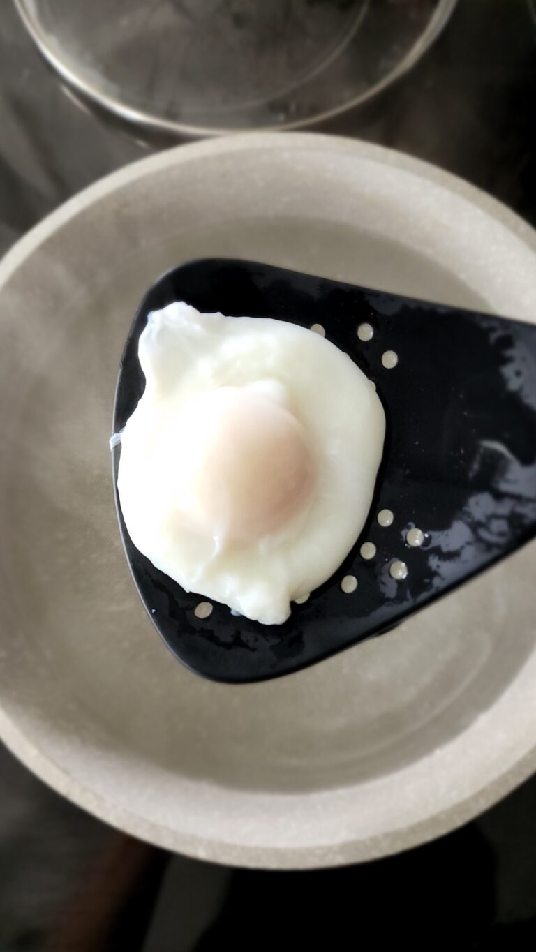 Draining the poached egg with a slotted spoon