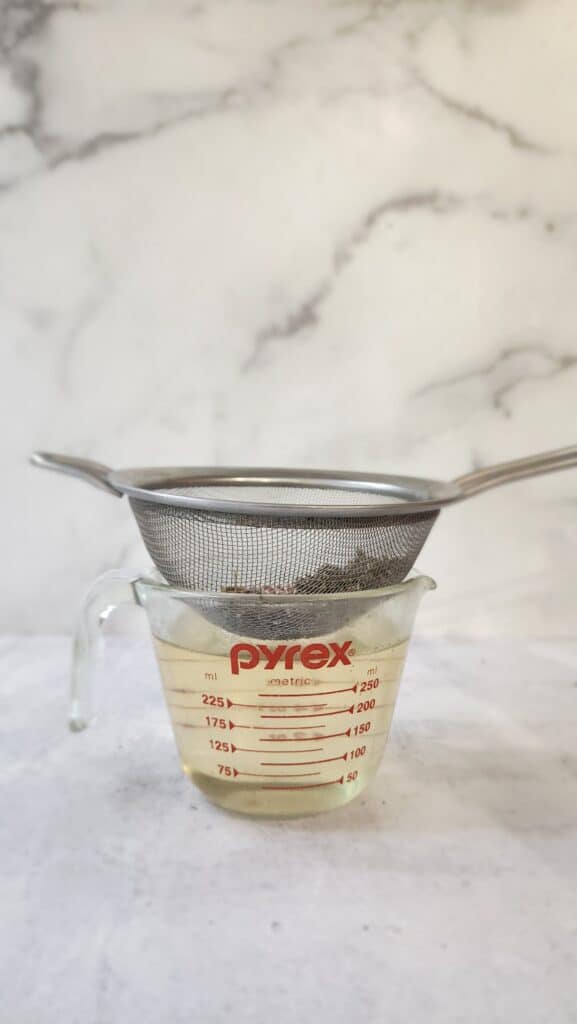 strainer removing the lavender strained into a measuring cup