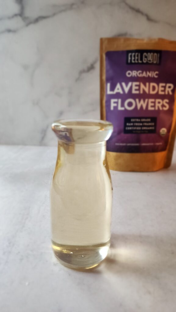 Final lavender simple syrup in a glass bottle with lavender brand in the back