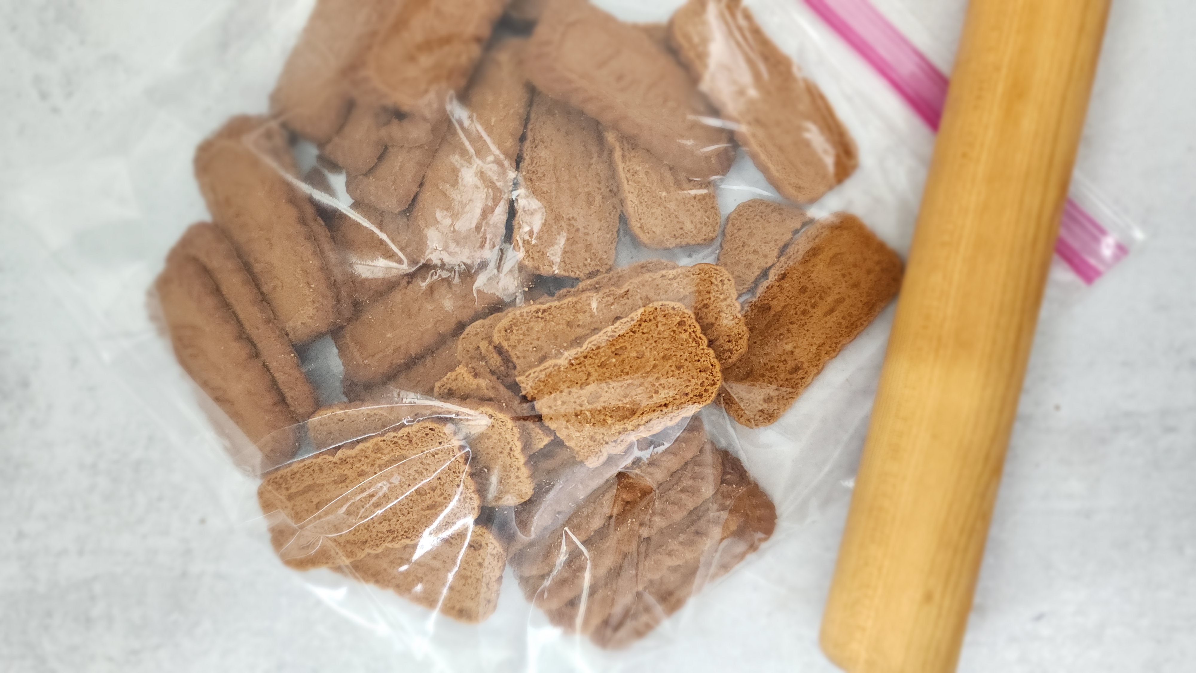 biscoff cookies in a plastic bowl ready to roll into crumbs with a rolling pin