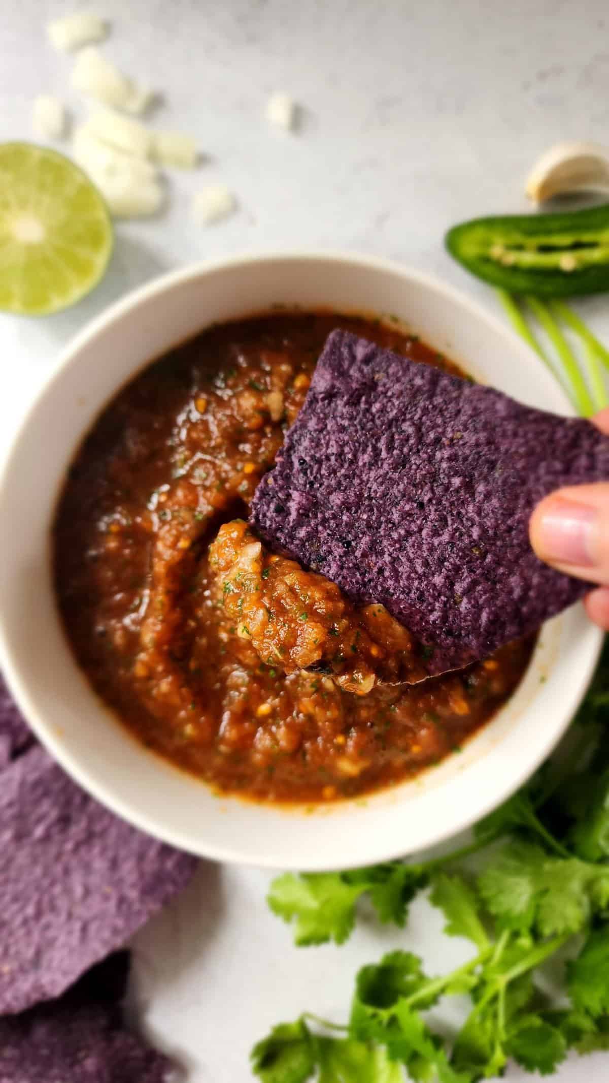 Easy Homemade Salsa in a bowl, with a hand dipping in a chip
