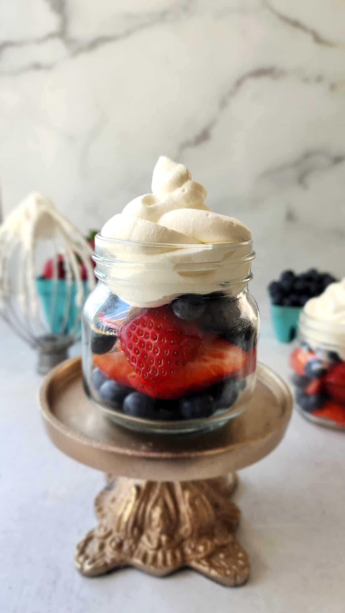 final shot of a small glass with berries and fresh whipped cream on top