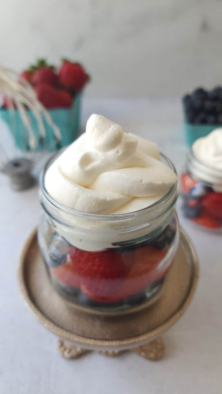 top shot of a glass with fresh berries and homemade whipped cream