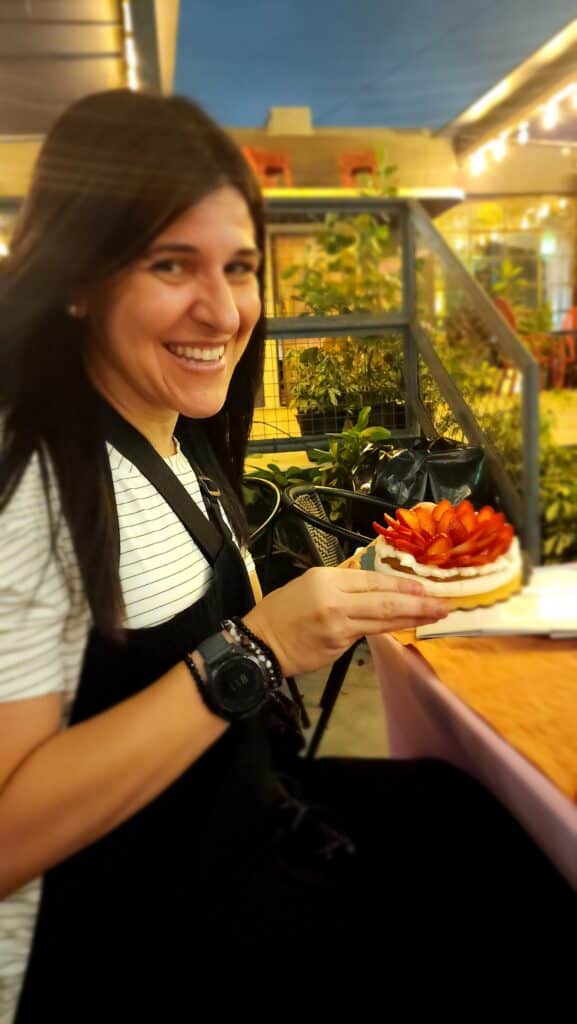 picture of me holding a pavlova with a HUGE smile on my face for completing my master's