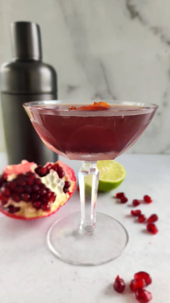 Festive glass with a Pomegranate Cosmopolitan with a cut open pomegranate and arils