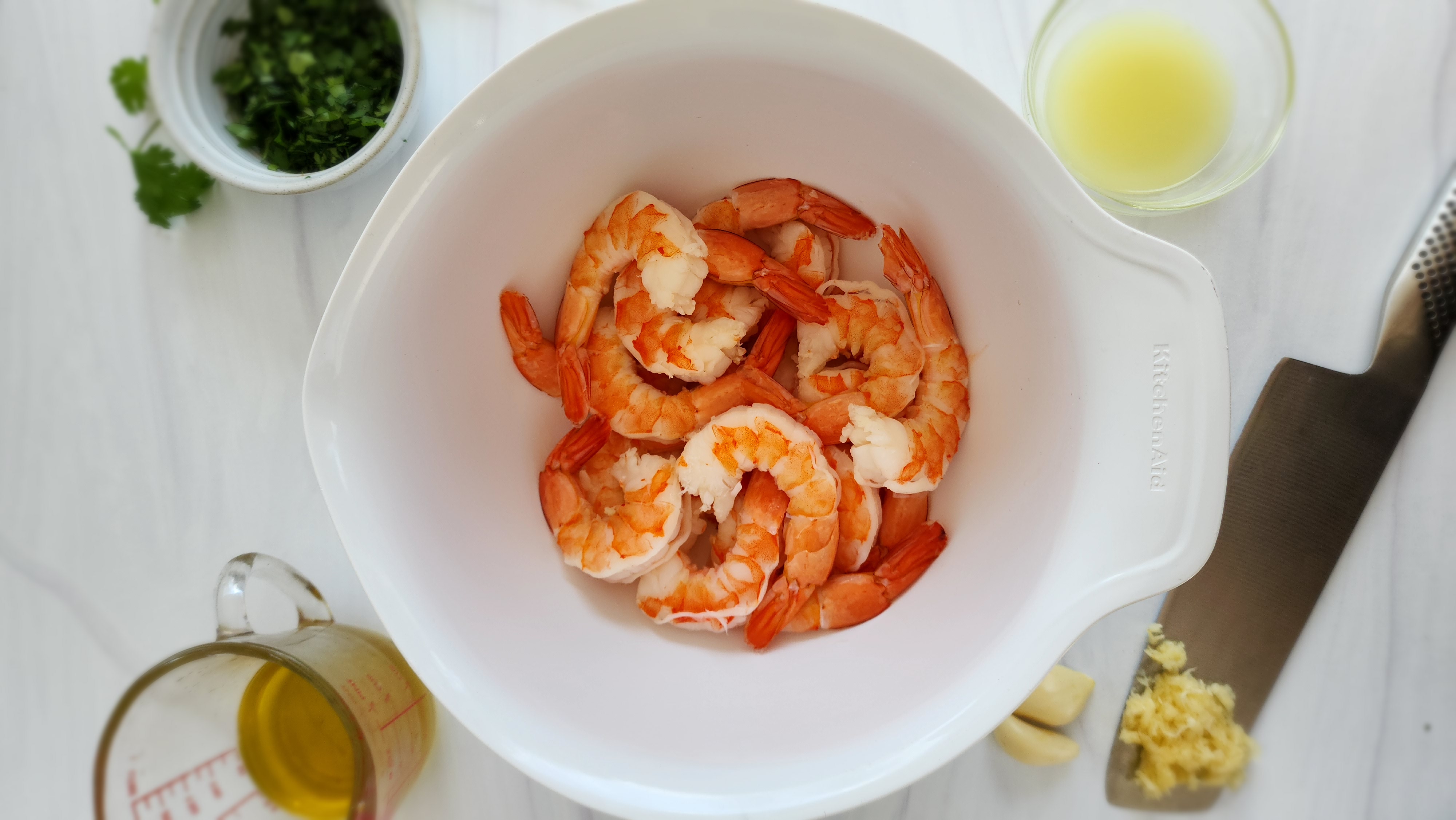 ingredients all laid out for key lime shrimp: shrimp in a bowl, garlic, olive oil, key lime juice, cilantro (set off to the side)