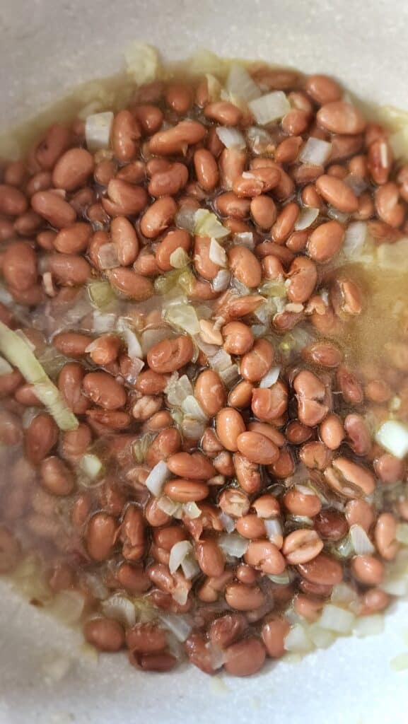 Adding in beans and broth to make homemade refried beans