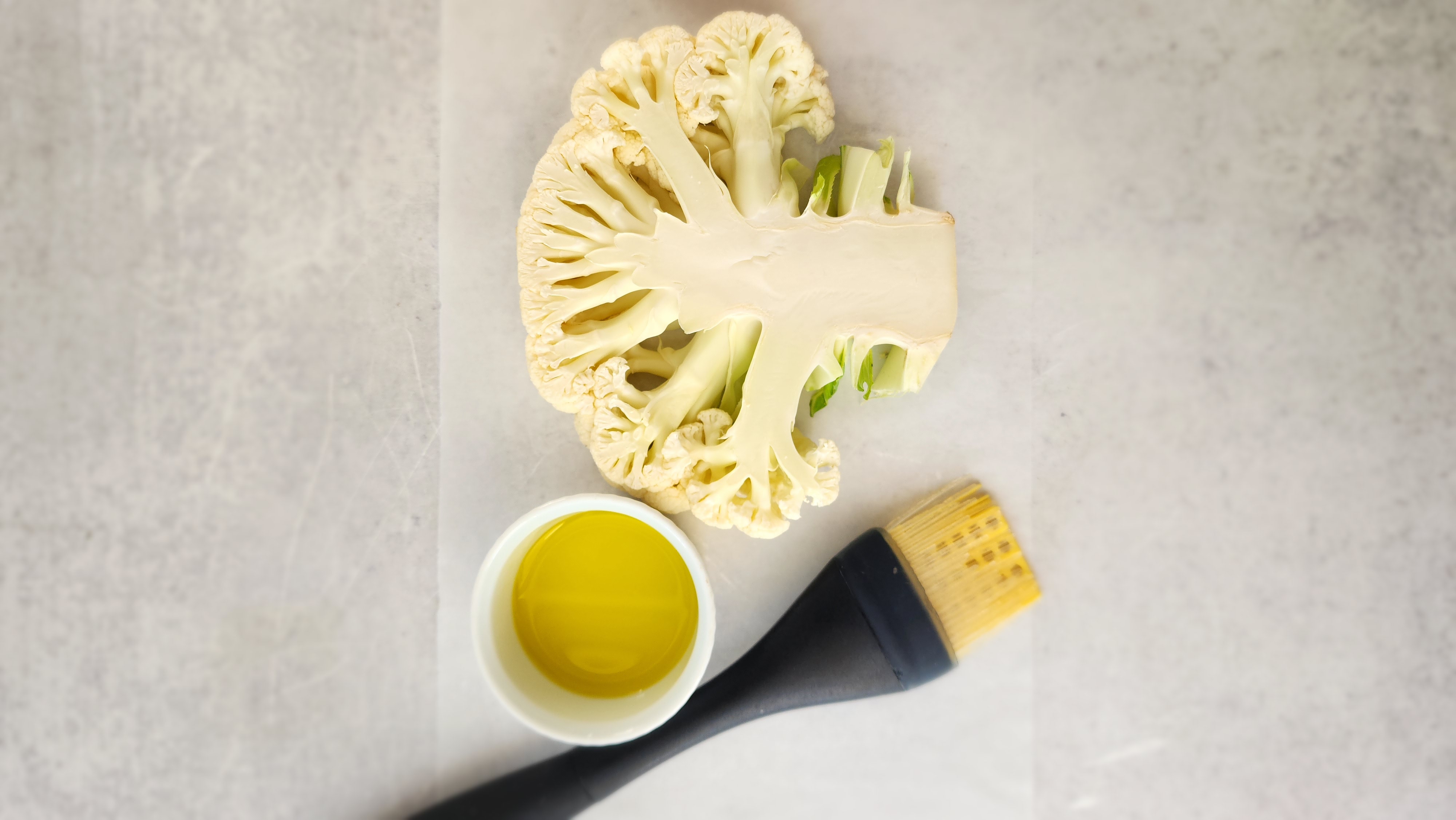 Cut of cauliflower with olive oil and a brush