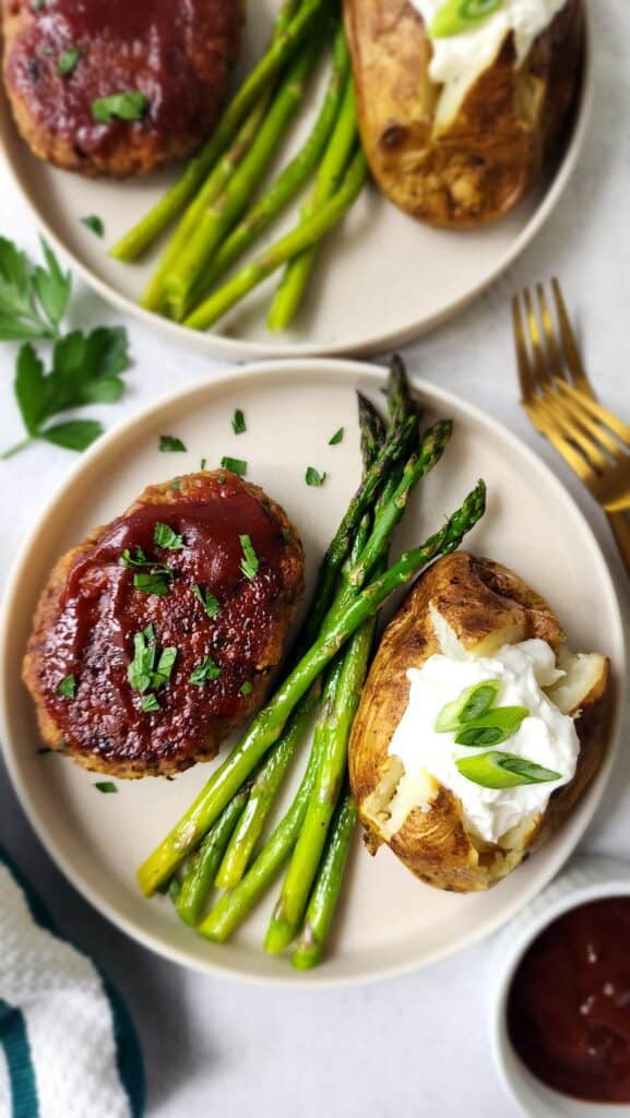 plate full of meatless meatloaf, roasted asparagus, and an air fryer baked potato with a dollop of Greek Yogurt
