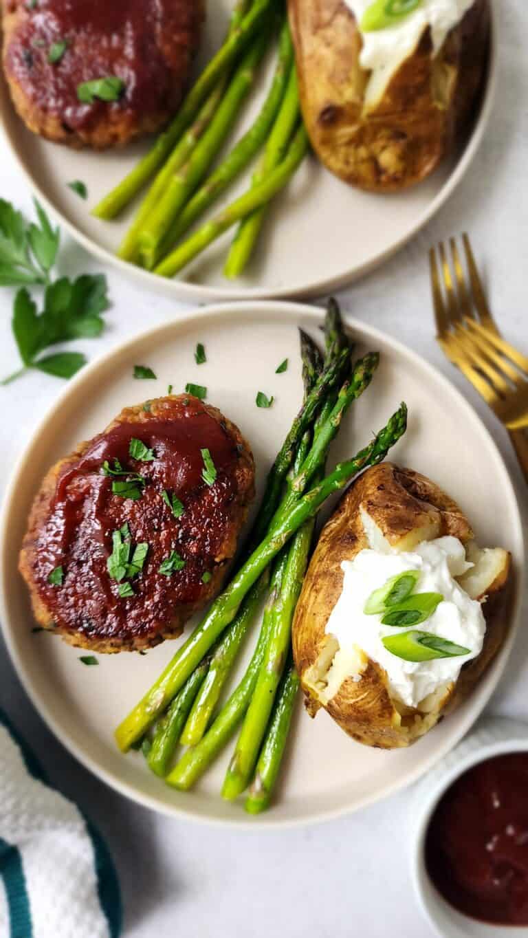 plate full of meatless meatloaf, roasted asparagus, and an air fryer baked potato with a dollop of Greek Yogurt