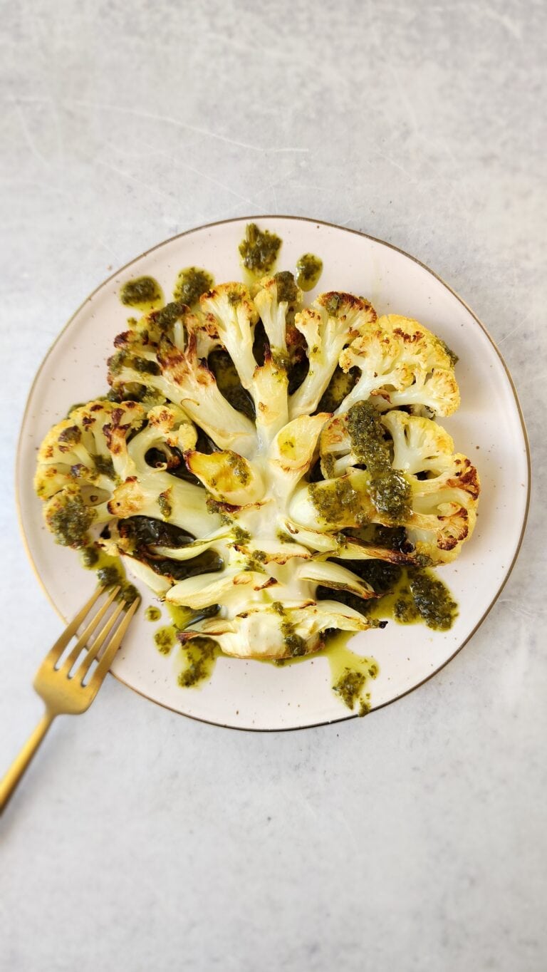 plate of roasted cauliflower 'steaks' drizzled with chimichurri sauce