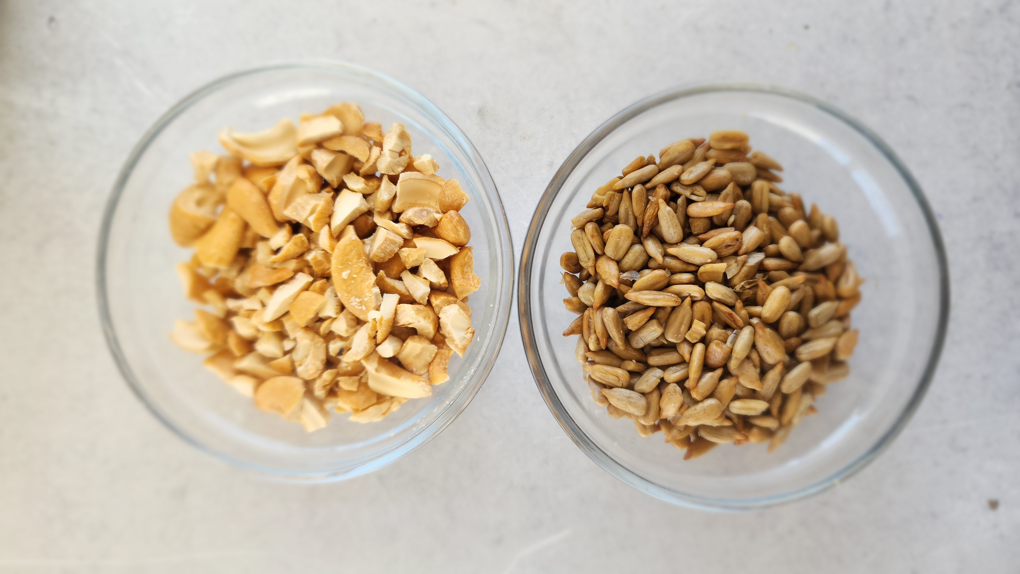 two small bowls filled with cashews and sunflower seeds for broccoli salad