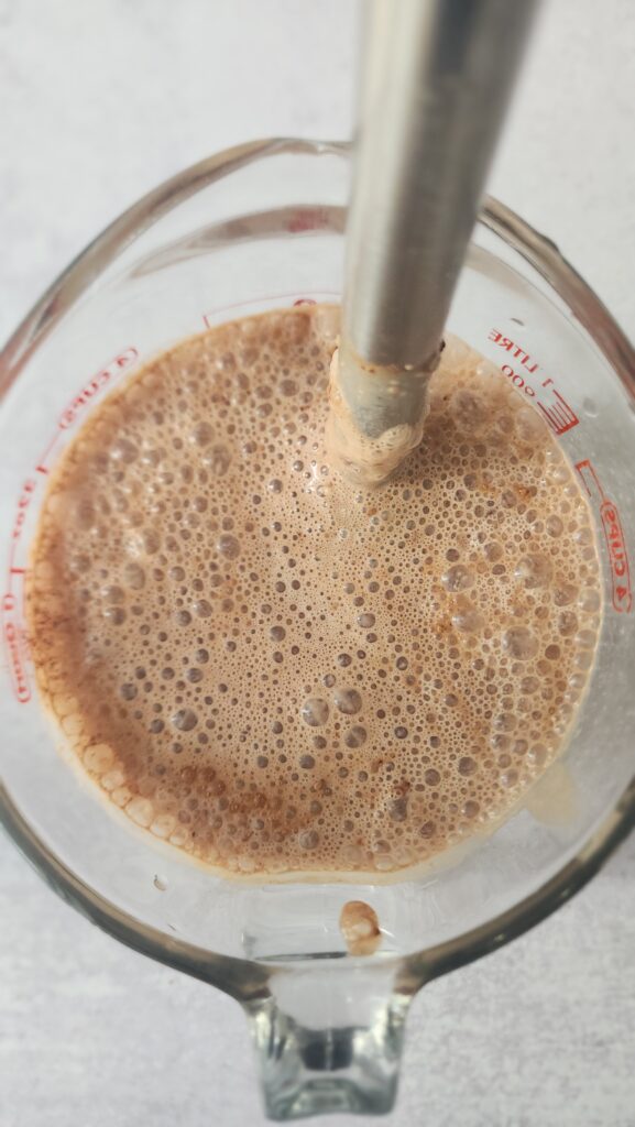 using an immersion blender to blend the cocoa powder into the milk and Greek yogurt mixture for chocolate chia seed pudding