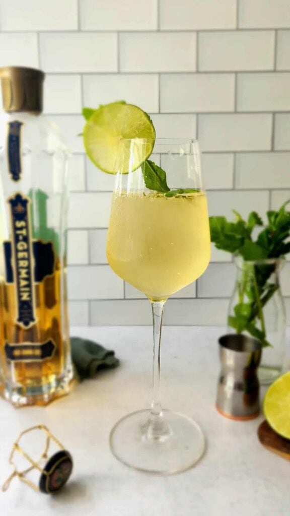 glass of Hugo Spritz with a lime and mint garnish