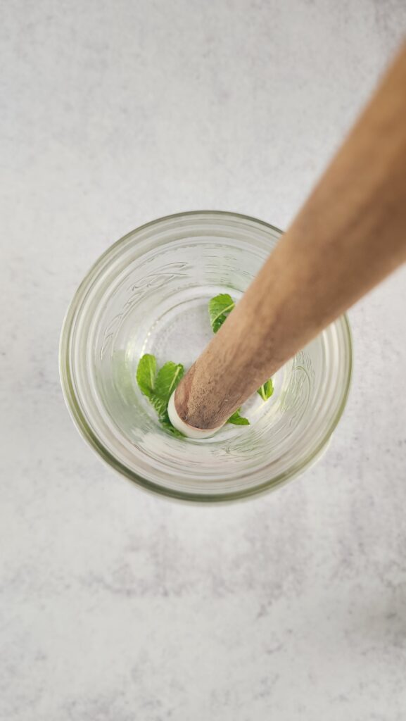 muddler muddling mint in a mason jar for the Rosé Hugo Spritz