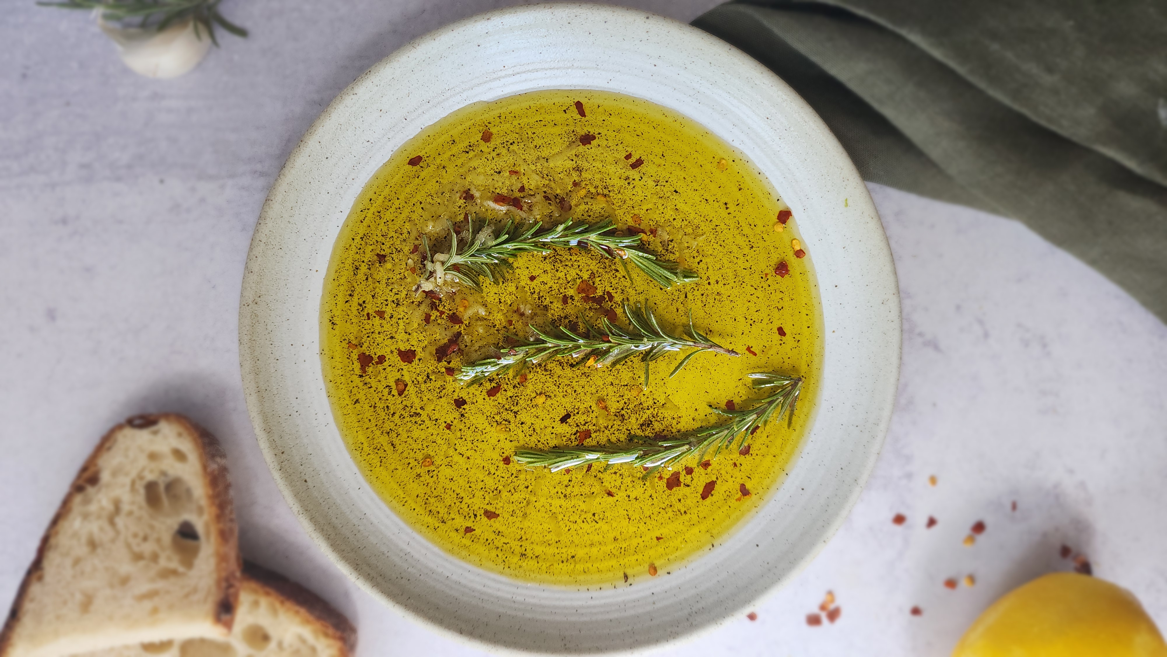 plate of bread dipping oil with a slice of bread to the side ready to be dipped