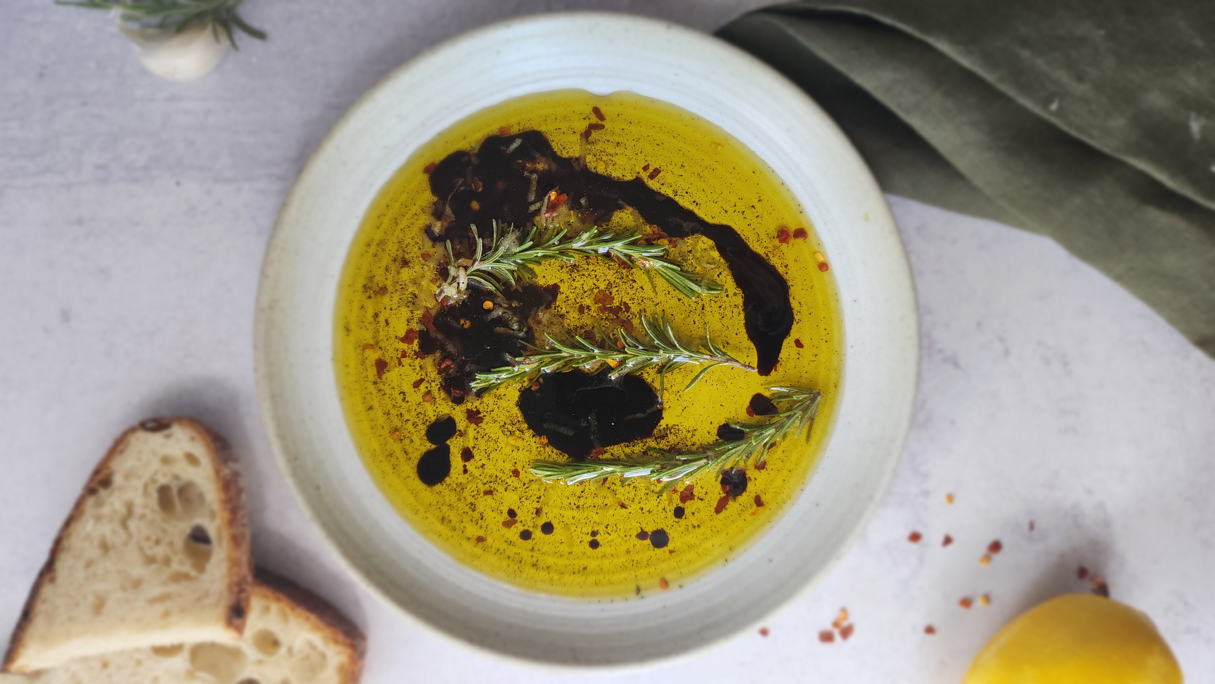 plate of bread dipping oil with bread to the side ready to dip