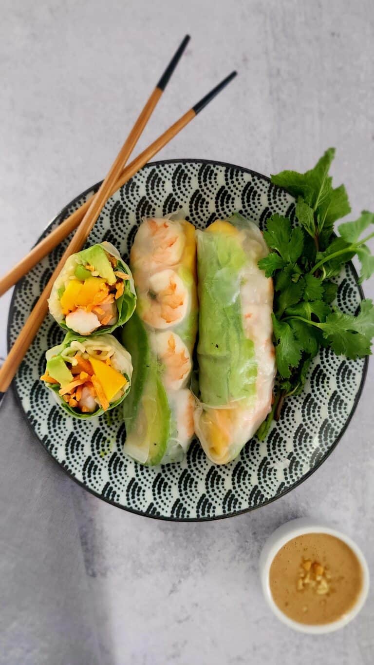 2 full shrimp spring rolls an one roll cut in half on a plate