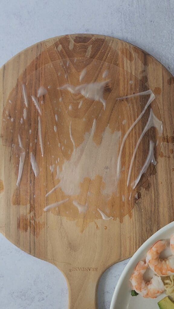 cutting board with a soaked rice paper to make easy shrimp spring rolls