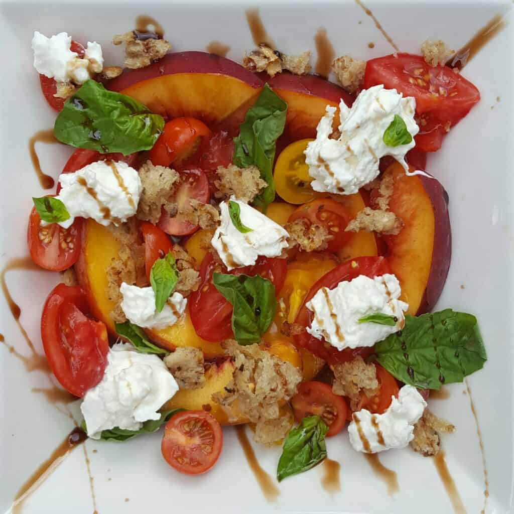 plate of stone fruit salad with burrata and a balsamic glaze