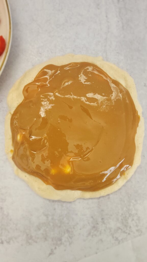 The makings of strawberry pavlova step by step and in this picture the pavlova is on the bottom with a layer of dulce de leche