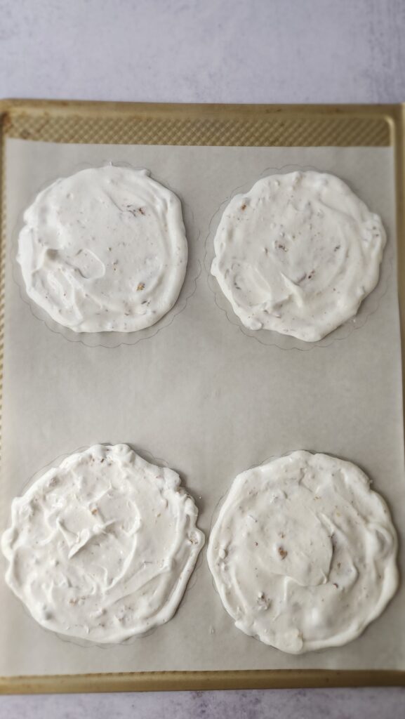 egg whites that have been beaten to make meringue spread into 5-inch circles ready to be baked for strawberry pavlova