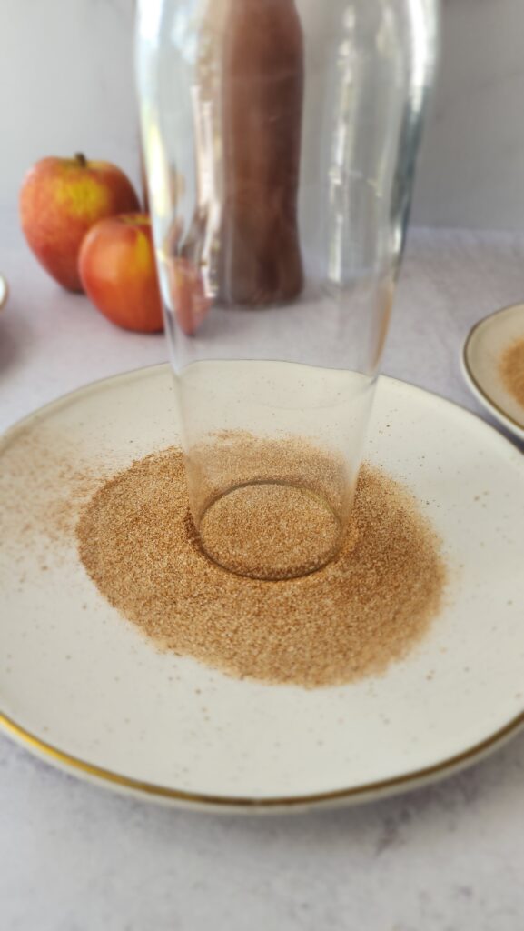 glass with honey on the rim being dipped into the cinnamon sugar mix for apple cider mimosas
