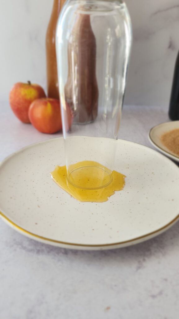 glass being dipped into honey on a plate for rimming apple cider mimosas