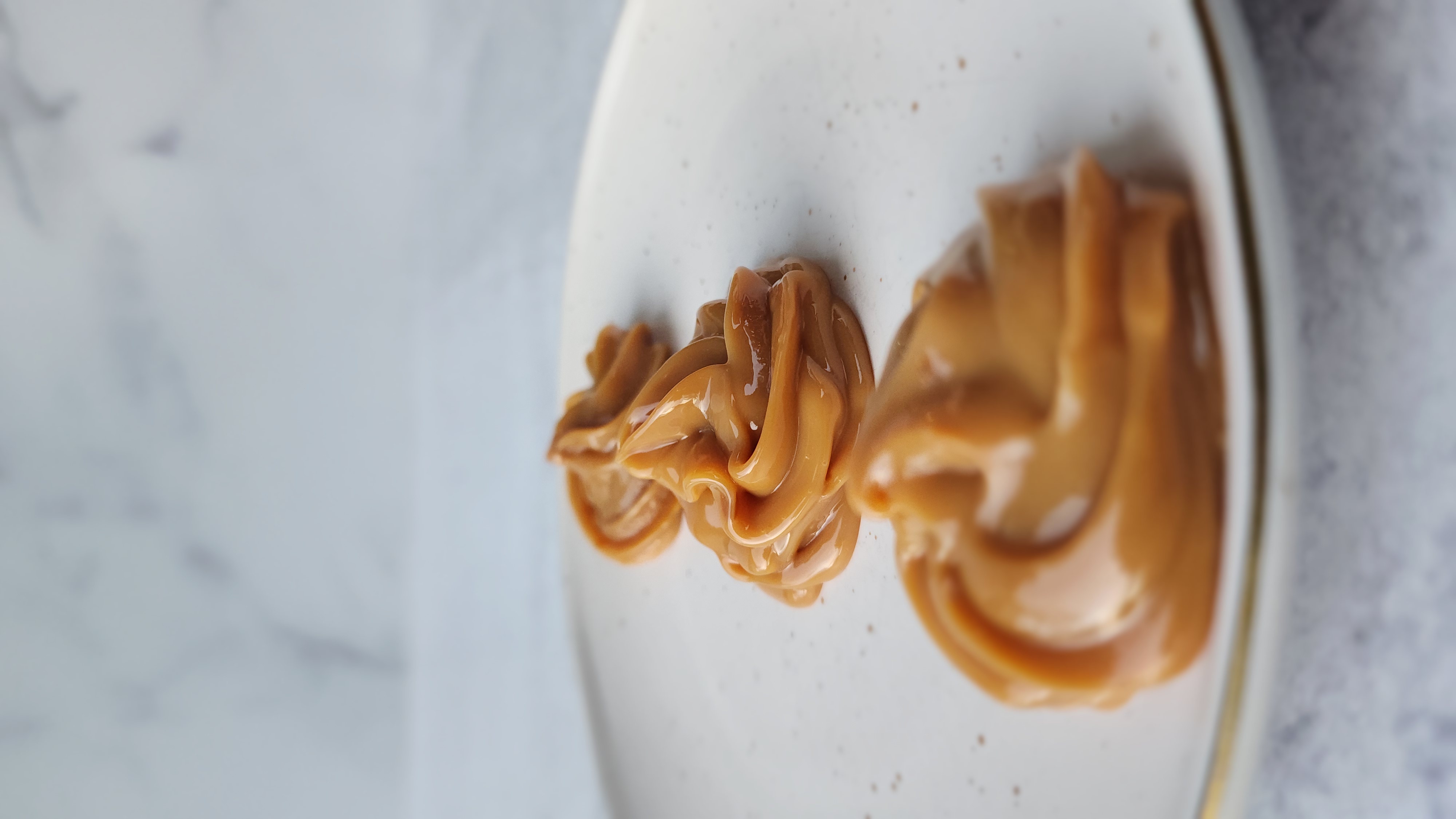 plate of three dollops of dulce de leche piped on a plate for Instant Pot Dulce de Leche