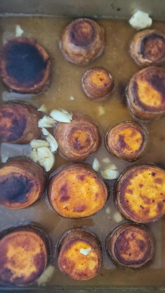pan with broth and smashed garlic for melting sweet potatoes