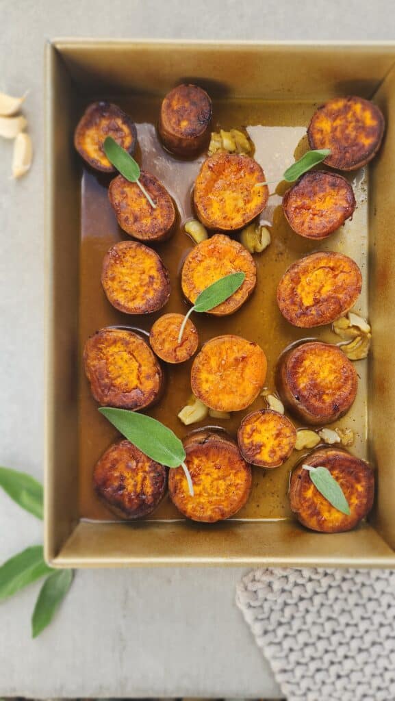 baking pan of melting sweet potatoes with a few sage leaves garnished on top