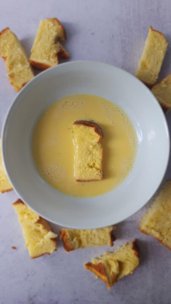 Brioche bread dipped in beaten egg to make Air Fryer French Toast Sticks