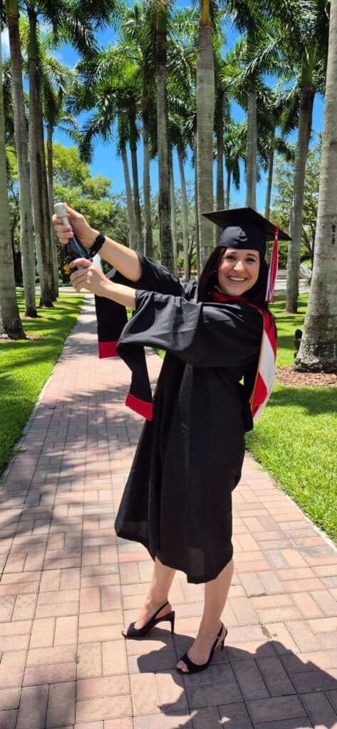 picture of myself in my cap and gown for my master's popping a bottle of champagne