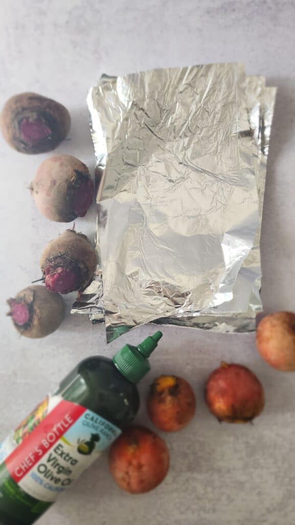 aluminum foil squares, olive oil, and beets to prepare to roast beets