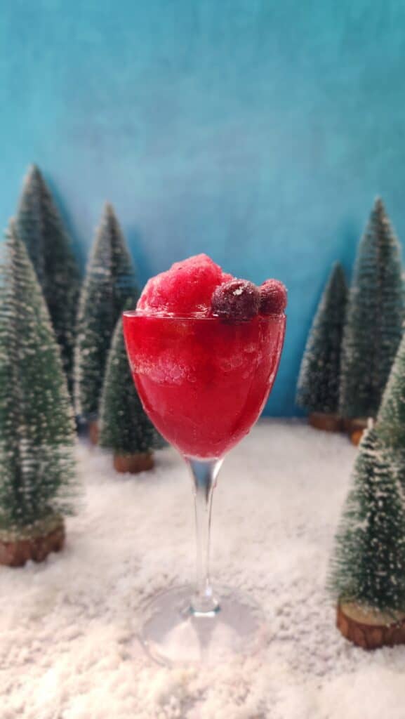 glass of Frozen Pomegranate Mocktails on fake snow in a fake forest