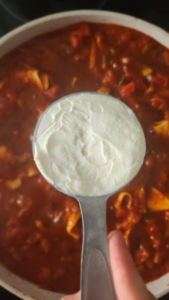 ricotta cheese being added to the skillet lasagna