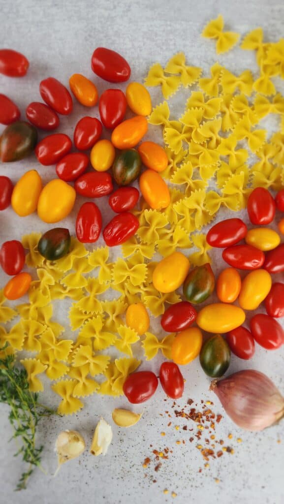 ingredients for baked feta pasta: pasta, tomatoes, shallot, thyme, olive oil, pepper, red pepper flakes