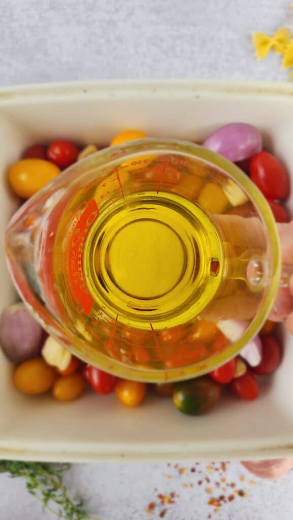 olive oil getting ready to spread over the ingredients for baked feta pasta