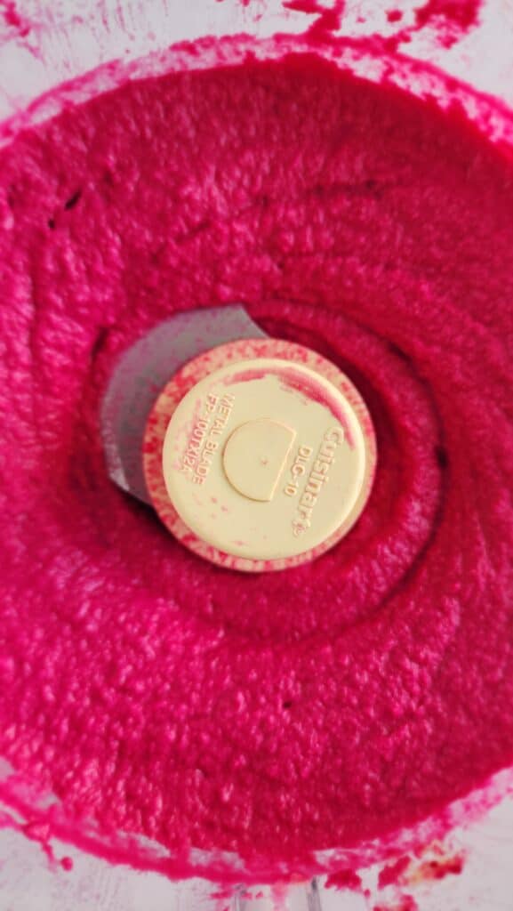 adding cold water to make the roasted beet hummus smooth