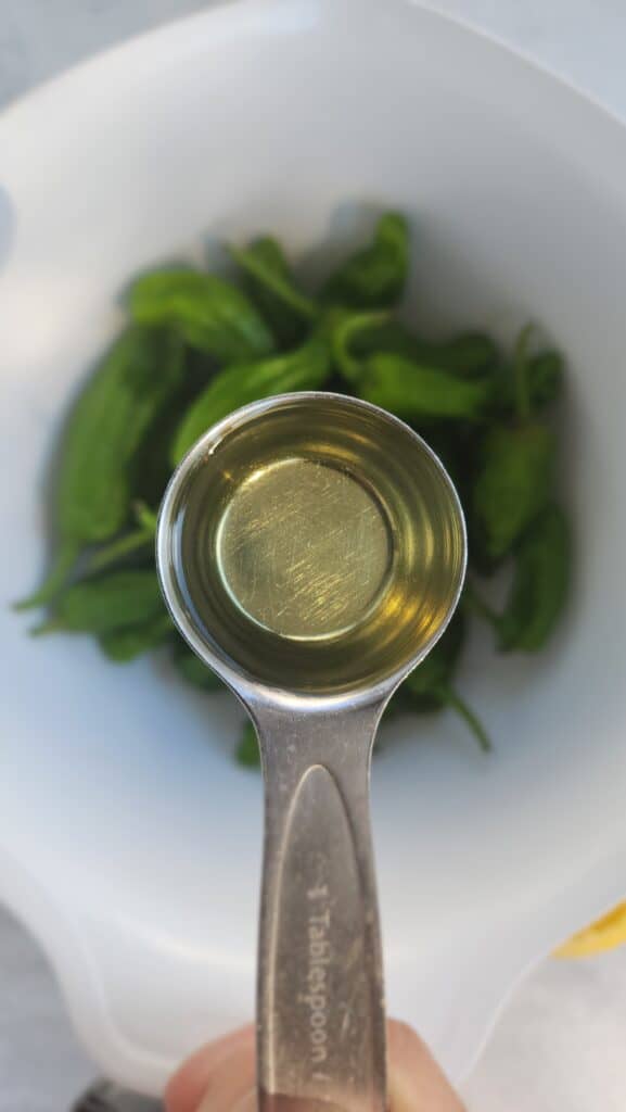 olive oil about to be added to shishito peppers